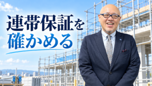 建設現場を背景に立つたちばなはじめ